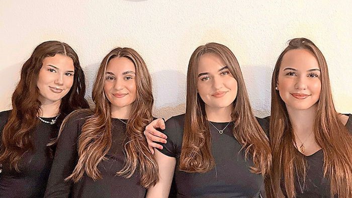 4 weibliche Jugendliche in schwarz gekleidet, die freundlich in die Kamera blicken.